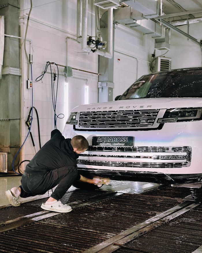 A worker cleaning a Range Rover in an indoor car wash with attention to detail.