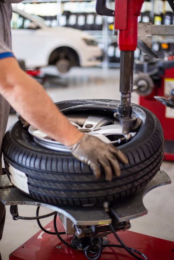 Close-up of an auto mechanic changing a tire with precision equipment in a professional workshop.