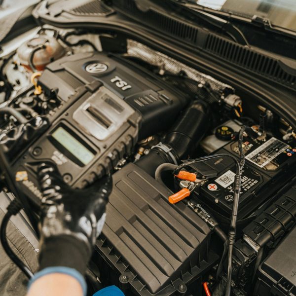 Close-up view of a mechanic diagnosing a Volkswagen engine with specialized equipment.